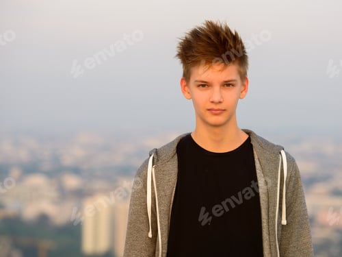Preview: Young handsome teenage boy against view of the city outdoors