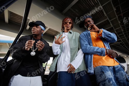 Preview: Three young stylish African American men in trendy attire standing by car
