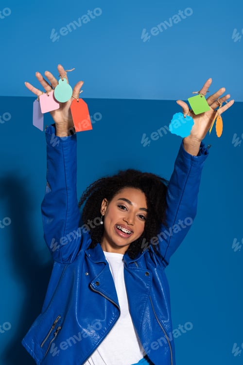 Preview: happy african american woman with empty labels on hands on blue background