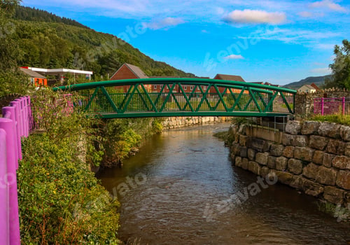 Preview: Green metal bridge over a calm river with stone embankments in Cardiff, Wales