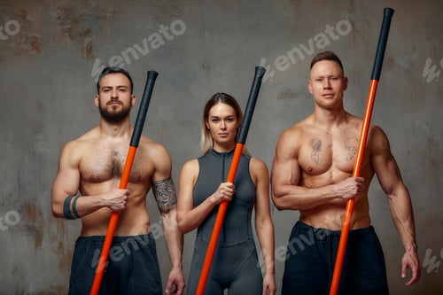 Preview: Two men and woman aikido fighters with wooden fight stick posing in studio, fight demonstration