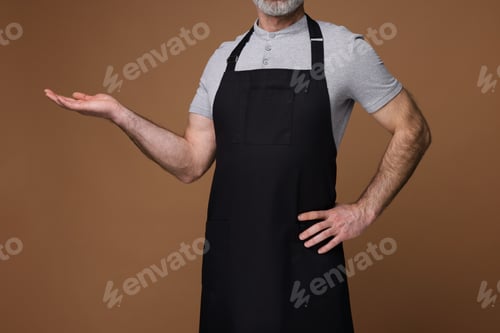 Preview: Man wearing kitchen apron on brown background, closeup. Mockup for design