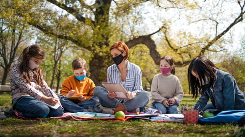 Preview: Teacher with small children sitting outdoors, learning group education and coronavirus concept.