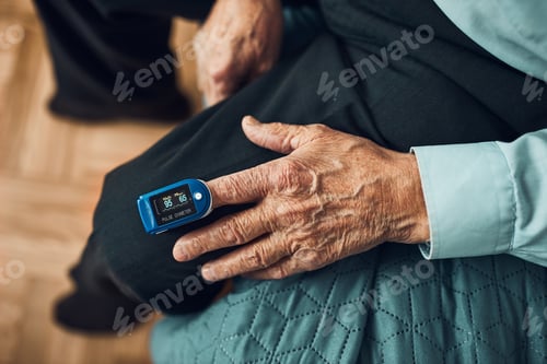 Preview: Senior man measuring the degree of oxygen saturation of the blood at home using pulse oximeter