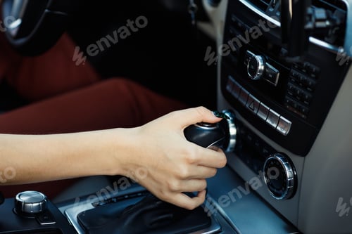 Preview: Young woman driver hands holds close up gear shift knob car.