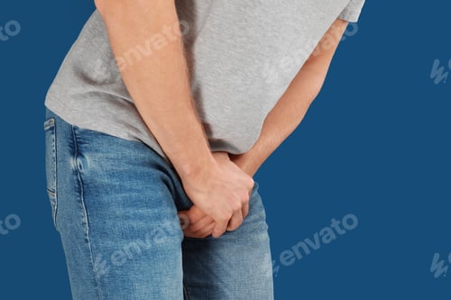 Preview: Man suffering from pain on blue background, closeup. Urology problems