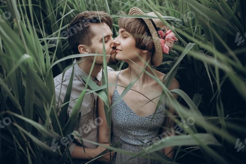Preview: Stylish rustic bride and groom embracing in windy high reed