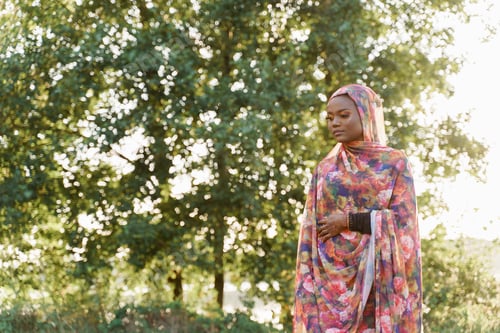 Preview: Muslim girl in hijab looking left, African woman in colorful national dress outdoors