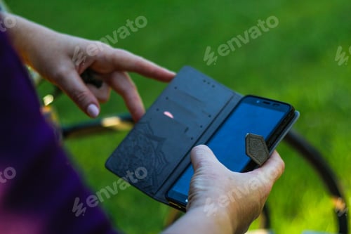 Preview: close-up female hands searching on the phone outside, outdoor