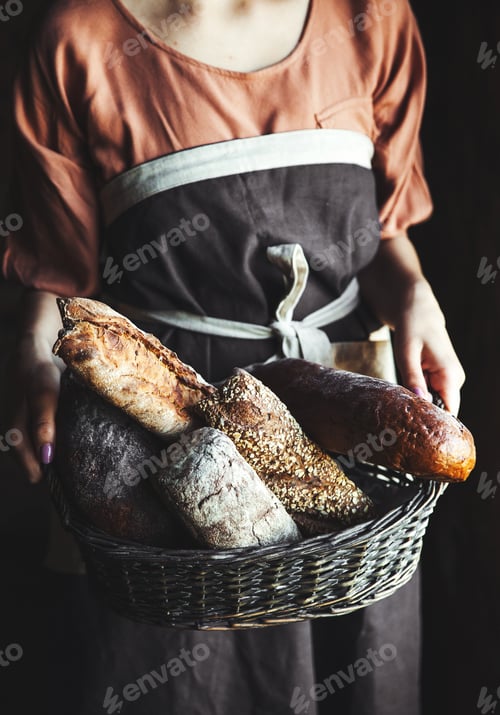 Preview: French baguettes in female hands on a black background. homemade baking