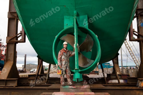 Preview: Portrait of male ship painter in front of green ship propeller