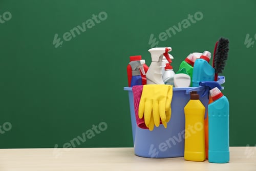 Preview: Bucket with cleaning supplies on table against color background. Space for text