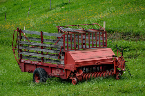 Preview: Red tractor collecting green grass and cultivating farmland in the countryside