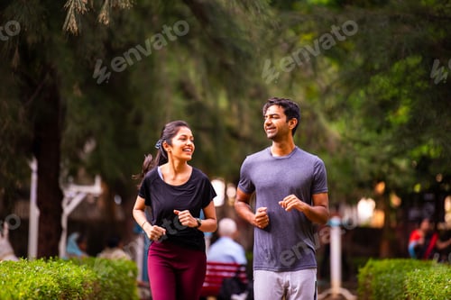 Preview: Indian young couple jogging in park enjoying morning fitness, outdoor freshness and bonding