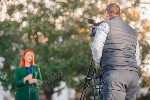 Preview: Cameraman recording a female journalist presenting news outdoors