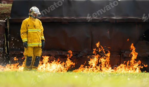 Preview: A firefighter in full protective gear standing through intense flames