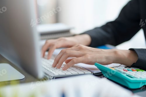 Preview: Close-up of a woman's hands sitting intently typing using laptop computer at the office fluently and