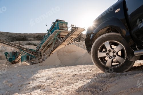 Preview: Black car with quarry equipment and stone crusher in operation on the background