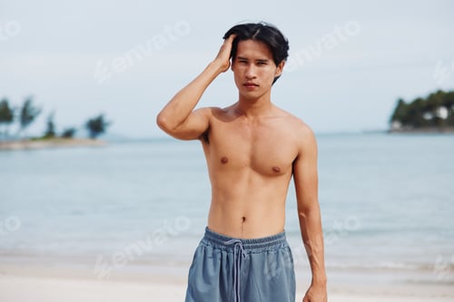 Preview: Smiling Asian Man On the Sandy Beach, Enjoying Summer Vacation near the Turquoise Ocean and Lush