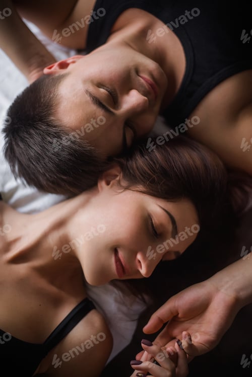 Preview: Top view of couple in love. Close-up portrait of the Lovers who lie on the bed at home, head to head