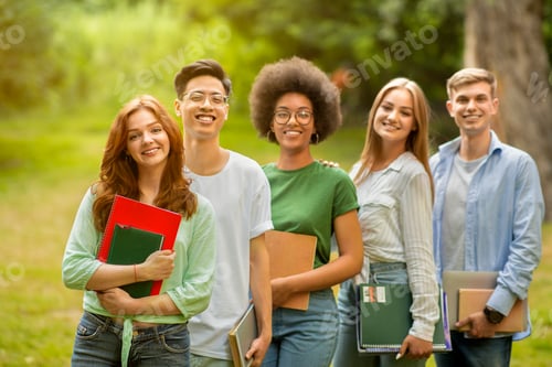 Preview: Group portrait of multiracial university students posing with workbooks outdoors at campus