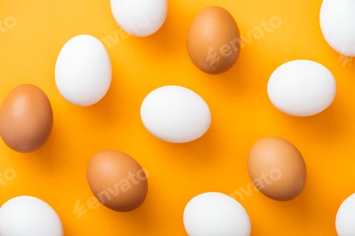 Preview: top view of whole white and brown fresh chicken eggs on bright orange background