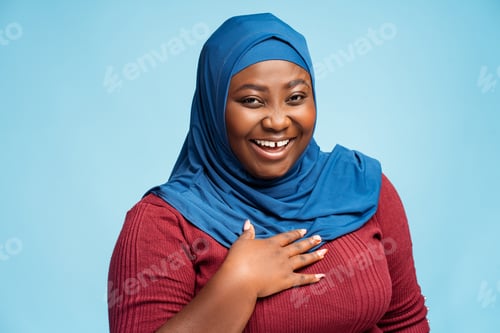 Preview: Portrait attractive smiling arabian woman wearing traditional hijab isolated on blue background