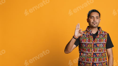 Preview: Man doing ok hand gesture, offering positive feedback, studio background