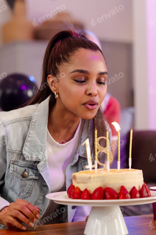 Visualização: Jovem mulher soprando velas no bolo de aniversário, comemorando o marco com alegria