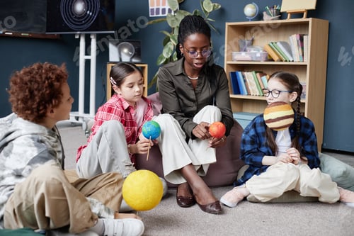 Preview: Black Woman Leading Preteen Children Discussing Model Planets Indoors