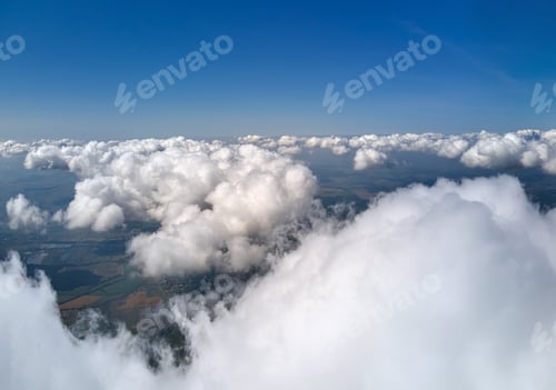 Preview: Aerial view from airplane window at high altitude of earth covered with white puffy cumulus clouds