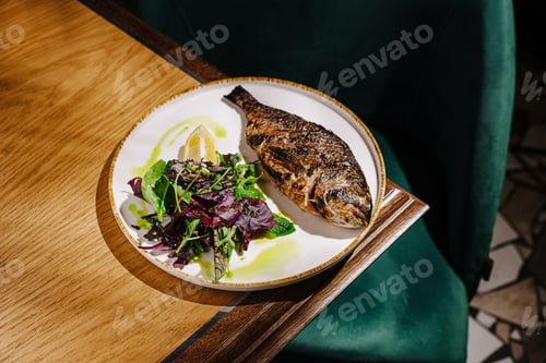 Preview: Grilled fish with fresh salad served on a white plate in a cozy restaurant