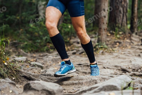 Preview: legs runner in compression sleeves on his feet run forest trail race over stones