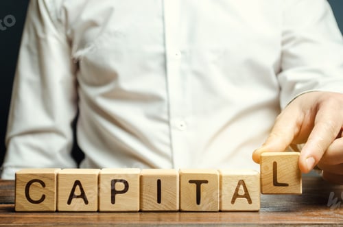 Preview: A man puts wooden blocks with the word Capital