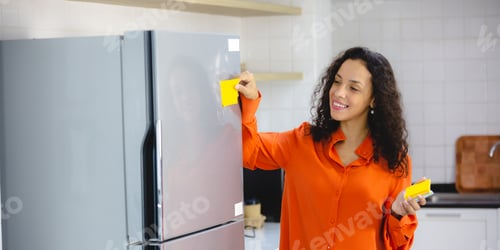 Preview: Young and organized female with curly hair in casual clothing making to-do and checklist