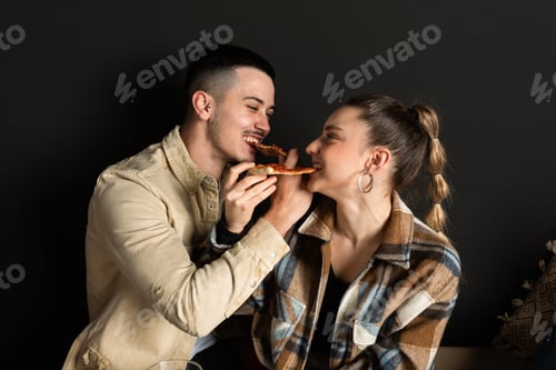 Preview: Loving Couple Sharing Pizza Against Dark Background