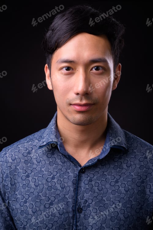 Preview: Young handsome Asian businessman against black background