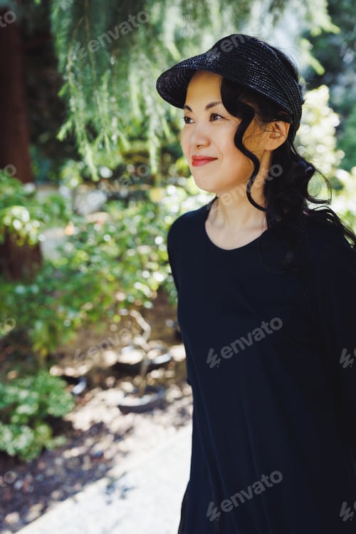 Preview: Middle-aged Japanese woman in black straw sun brim hat, summer park