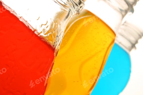 Preview: Closeup of three bottles of sugared drinks in yellow, blue and red colors, white background