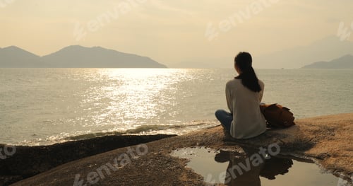 Preview: Woman looking at the sea under sunset