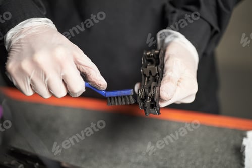 Preview: Young Adult Man Cleaning Bicycle Chain with Brush in Workshop