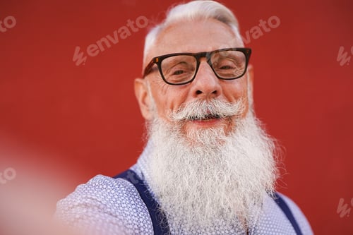 Preview: Happy hipster senior man smiling on camera while taking a selfie