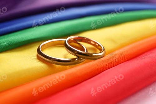 Preview: Wedding rings on rainbow LGBT flag, closeup