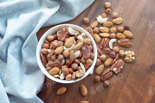 Preview: Wooden bowl with mixed nuts on table top view. Healthy food and snack
