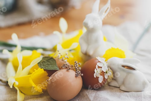 Preview: Stylish Easter eggs decorated with dry flowers on rustic linen napkin with daffodils and bunnies