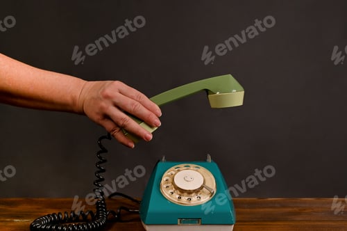 Preview: woman's hand puts down the receiver of an old vintage phone.