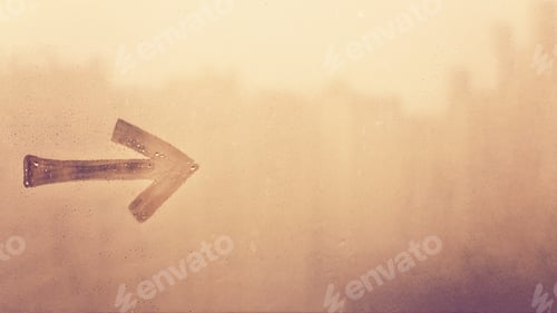 Preview: Hand drawn one arrow pointing to the right on foggy glass of yellow sunset window, copy space