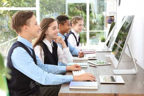 Preview: Teenage students in stylish school uniform at desks with computers