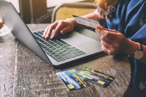 Preview: A woman holding credit cards while using laptop computer