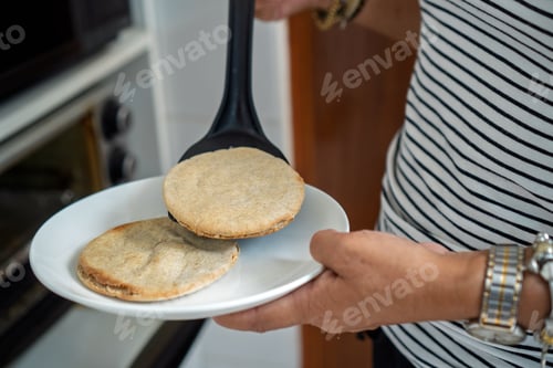 Preview: Person serving homemade arepas from oven onto plate